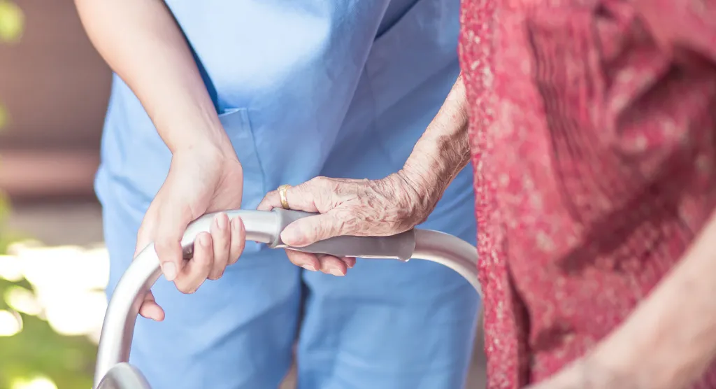 Care worker helping an older woman hold a walking frame
