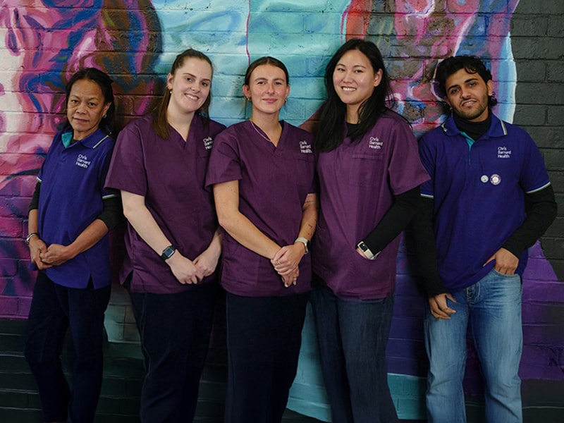 Five Chris Barnard Health team members standing together in front of a colourful mural
